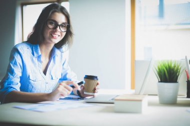 Ofis masasında oturan genç bir kadın dizüstü bilgisayar ekranına bakıyor. Genç kadın.