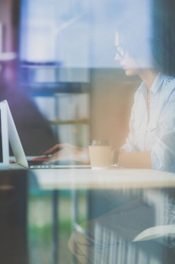 Ofis masasında dizüstü bilgisayarıyla oturan genç bir kadın. Pencereden bakıyor. Genç kadın.