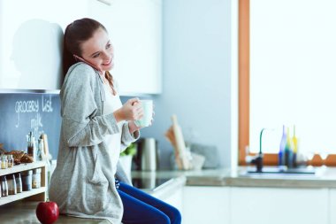 modern mutfakta otururken cep telefonu kullanan kadın.