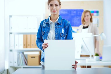 Masanın yanında duran iki genç kadın enstrüman, plan ve dizüstü bilgisayarla.