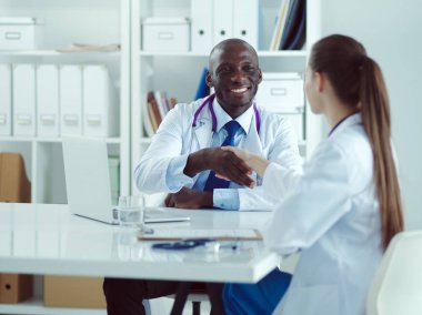 Ofiste tokalaşırken gülümseyen iki genç tıp adamı. Doktorlar. Takım çalışması.