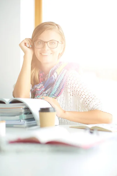 Jeune femme assise à un bureau parmi les livres. Étudiant — Photo