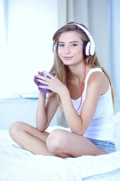 Retrato de una hermosa mujer en la mañana escuchando música sentada en la cama en casa. Retrato de mujer hermosa — Foto de Stock