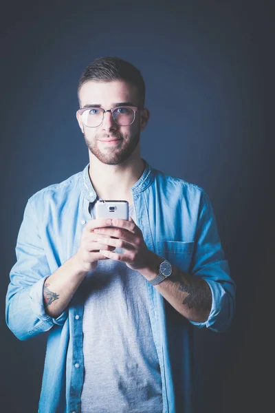 Sorridente giovane uomo in possesso di telefono mentre messaggistica di testo — Foto Stock