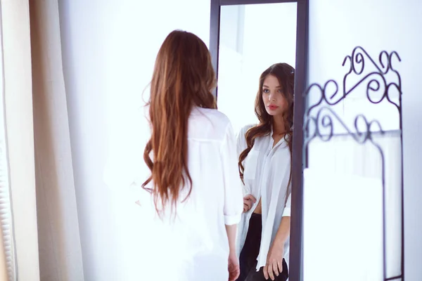 Mujer joven mirándose a sí misma reflejo en el espejo en casa. Mujer joven . — Foto de Stock