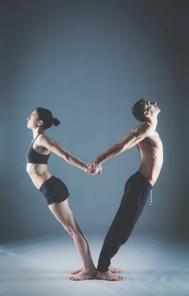 Casal jovem praticando acro ioga no tapete em estúdio juntos. Acroyoga. Um par de ioga. Parceiro ioga . — Fotografia de Stock