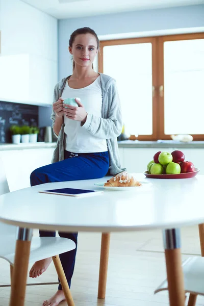 Lycklig kvinna dricka te i köket hemma. — Stockfoto