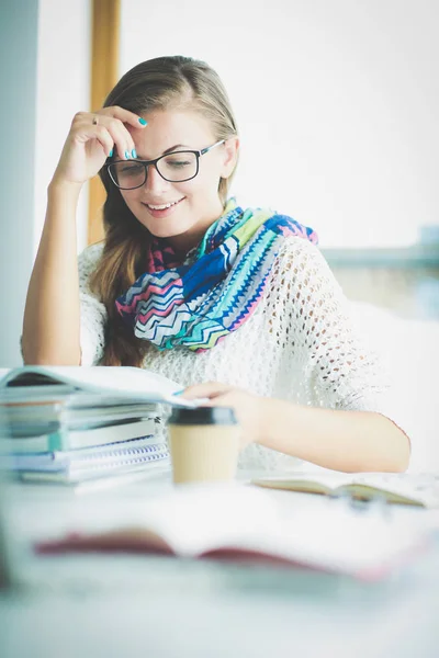 Jonge vrouw zit achter een bureau tussen de boeken. Studenten — Stockfoto