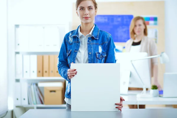 两名年轻妇女站在办公桌旁边，手里拿着仪器、计划和手提电脑. — 图库照片