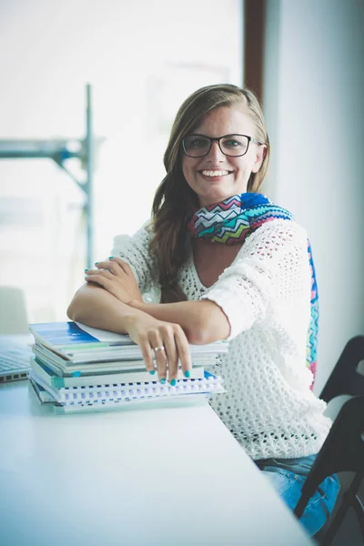 Młoda kobieta siedząca za biurkiem wśród książek. Student — Zdjęcie stockowe