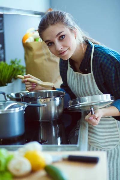 Mutfakta sobanın yanında duran genç bir kadın. .