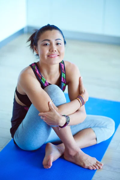 Porträtt av leende yoga kvinnan sitter på yogamattan efter träningspass på yogastudio. Yoga. Kvinna. — Stockfoto