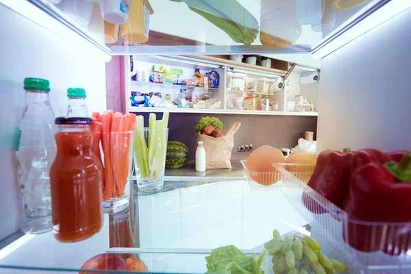 Portrait of female standing near open fridge full of healthy food, vegetables and fruits. Portrait of female — Stock Photo, Image