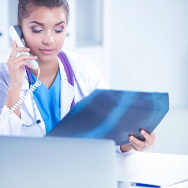 Masada oturan genç bayan doktor röntgen üzerinde çalışıyor.