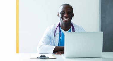 Masada dizüstü bilgisayarda çalışan genç bir Afrikalı doktor.