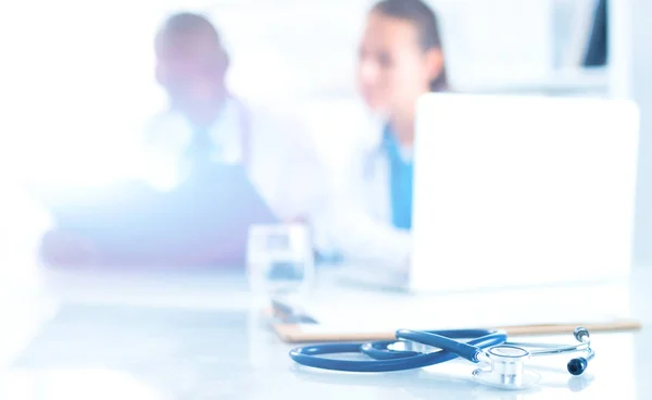 Stethoskop auf dem Schreibtisch und junge Mediziner als Hintergrund — Stockfoto