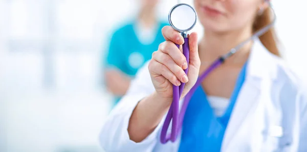 Doctora joven escuchando estetoscopio de pie en el hospital —  Fotos de Stock