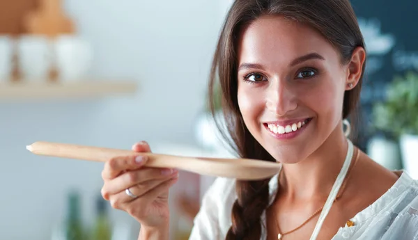 Mujer joven parada junto a la estufa en la cocina —  Fotos de Stock