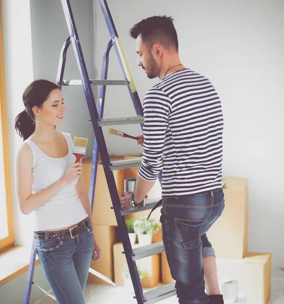 Portret gelukkig lachend jong koppel schilderij interieur wand van nieuwe huis — Stockfoto