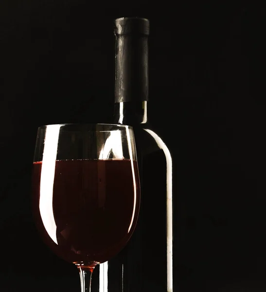 Glass of wine and a bottle on black background — Stock Photo, Image