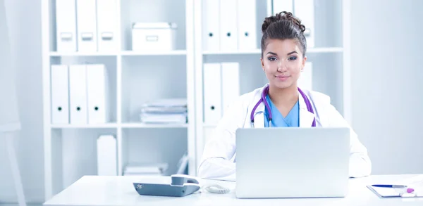 Médica mulher sentada na mesa e trabalhando em um laptop — Fotografia de Stock