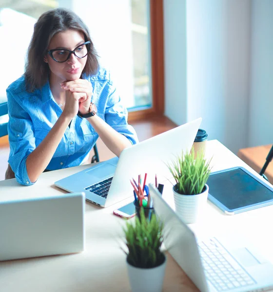 Mujer joven sentada en la mesa de la oficina con portátil — Foto de Stock