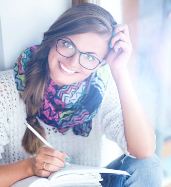 Kitapların arasında masa başında oturan genç bir kadın.