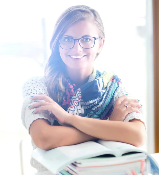 Junge Frau sitzt am Schreibtisch zwischen Büchern — Stockfoto