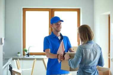 Mavi üniformalı gülümseyen kurye servis konseptine paket kutusu teslim eden teslimatçı. Mavi üniformalı gülümseyen teslimatçı.