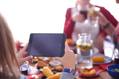 Ahşap masada otururken birlikte yemek yiyen bir grup insanın üst düzey görüntüsü. Masada yemek var. İnsanlar fast food yiyor..