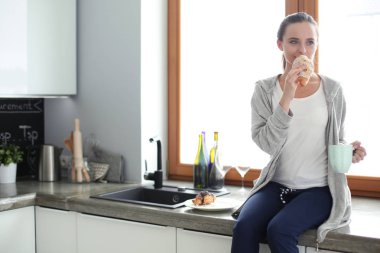 Mutfakta dijital tablet kullanan güzel genç bir kadın..