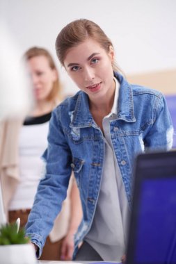 Masanın yanında duran iki genç kadın enstrüman, plan ve dizüstü bilgisayarla.