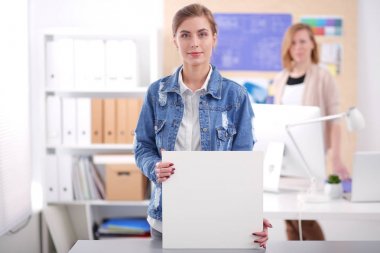 Masanın yanında duran iki genç kadın enstrüman, plan ve dizüstü bilgisayarla.