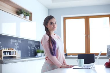 Cep telefonu ayakta modern mutfak kullanan kadın.