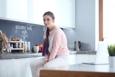 Mutfakta masada oturan genç kadın.