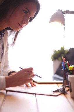 Masada oturan genç bir bayan. İş kadınıyım. Çizim. Öğrenci. İş yeri. Masa.