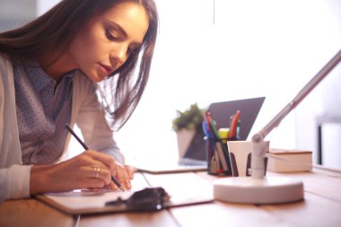 Masada oturan genç bir bayan. İş kadınıyım. Çizim. Öğrenci. İş yeri. Masa.