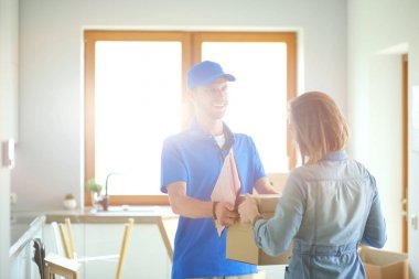 Mavi üniformalı gülümseyen kurye servis konseptine paket kutusu teslim eden teslimatçı. Mavi üniformalı gülümseyen teslimatçı.