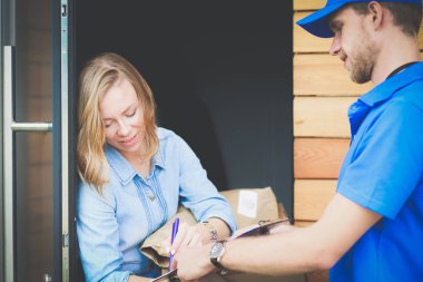 Mavi üniformalı gülümseyen kurye servis konseptine paket kutusu teslim eden teslimatçı. Mavi üniformalı gülümseyen teslimatçı.