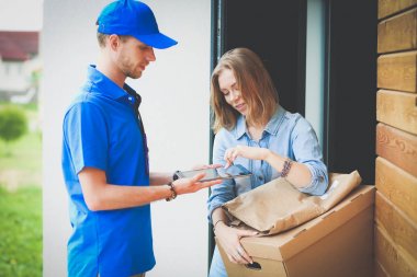 Mavi üniformalı gülümseyen kurye servis konseptine paket kutusu teslim eden teslimatçı. Mavi üniformalı gülümseyen teslimatçı.