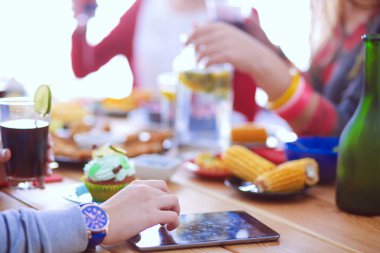 Ahşap masada otururken birlikte yemek yiyen bir grup insanın üst düzey görüntüsü. Masada yemek var. İnsanlar fast food yiyor..