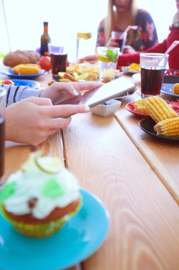 Ahşap masada otururken birlikte yemek yiyen bir grup insanın üst düzey görüntüsü. Masada yemek var. İnsanlar fast food yiyor..