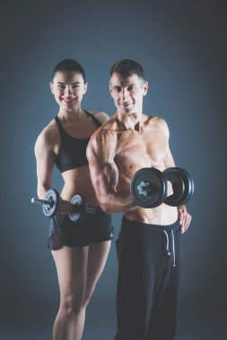 Atletik erkek ve kadın ile bir dumbells. Kişisel fitness eğitmeni. Kişisel eğitim.
