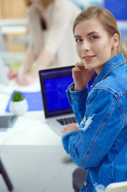 İki genç kadın masada enstrümanlar, planlar ve dizüstü bilgisayarlarla oturuyor..