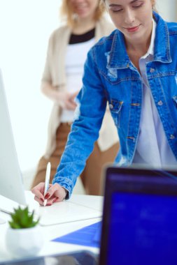 Masanın yanında duran iki genç kadın enstrüman, plan ve dizüstü bilgisayarla.