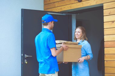 Mavi üniformalı gülümseyen kurye servis konseptine paket kutusu teslim eden teslimatçı. Mavi üniformalı gülümseyen teslimatçı.