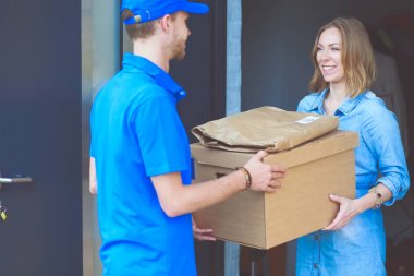 Mavi üniformalı gülümseyen kurye servis konseptine paket kutusu teslim eden teslimatçı. Mavi üniformalı gülümseyen teslimatçı.