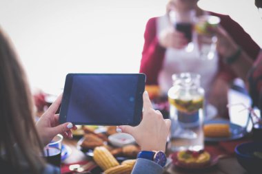 Ahşap masada otururken birlikte yemek yiyen bir grup insanın üst düzey görüntüsü. Masada yemek var. İnsanlar fast food yiyor..