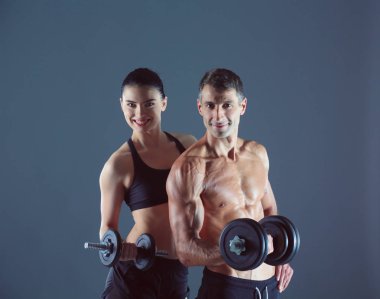 Atletik erkek ve kadın ile bir dumbells. Kişisel fitness eğitmeni. Kişisel eğitim.