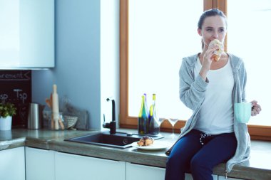 Mutfakta dijital tablet kullanan güzel genç bir kadın..
